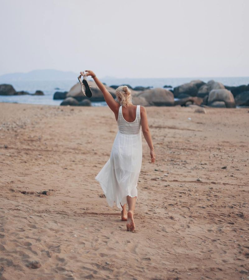 A woman in a calm, focused pose performing a fluid cardio movement in a minimalist studio.